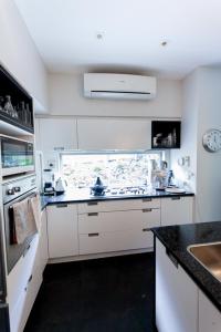 cocina blanca con fregadero y fogones en Artist Photographers Home Studio, en Auckland