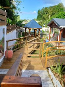 una terraza de madera con bancos y cenadores en Bienvenue chez Angie en Les Abymes