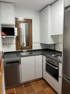 een keuken met witte kasten en roestvrijstalen apparaten bij Comodo apartamento en Bahia de la Plata in Zahara de los Atunes