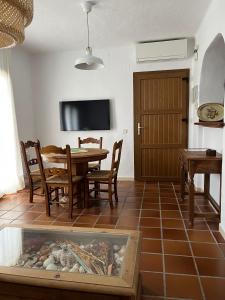 een eetkamer met een tafel, stoelen en een tv bij Comodo apartamento en Bahia de la Plata in Zahara de los Atunes