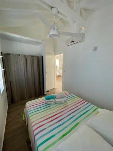 a room with a bed with a colorful striped blanket at Au coin des baigneuses in Saint-François +14 photos