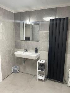 a bathroom with a sink and a black shower curtain at Rock Lane Rooms in Birkenhead