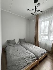 a bedroom with a large bed with a chandelier at Modern 4-Room compact flat with parking in Riga in Dreiliņi