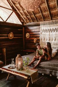 un homme et une femme assis sur un lit dans une pièce dans l'établissement Madre Tierra Eco Habitat, à Puerto Morelos