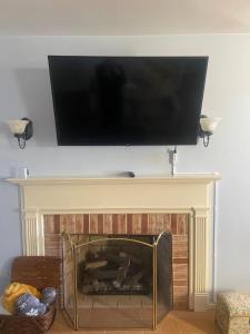 a flat screen tv hanging above a fireplace at Weaverling House- Historic Stay in Smalltown America in Everett