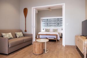 een woonkamer met een bank en een bed bij Niu Beach Hôtel Moorea in Moorea