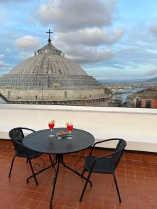a table and chairs on a balcony with a church at Lucullo's Rooftop in Naples