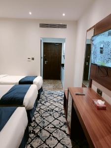 a hotel room with two beds and a flat screen tv at فندق نجمة العزيزية Star AL Aziziyah in Makkah