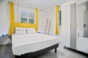 - une chambre avec un lit et une tête de lit jaune dans l'établissement Le Havre Vert avec Piscine et Kiosque, à Saint-Joseph