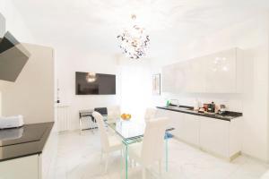 a white kitchen with a glass table and white chairs at Exclusive with Jacuzzi between Portofino and 5 Terre in Chiavari