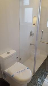 a white bathroom with a toilet and a shower at Pool View Studio Apartment in Candolim Beach Resort in Baga