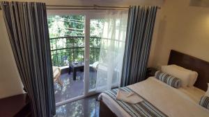 1 dormitorio con cama y ventana grande en Pool View Studio Apartment in Candolim Beach Resort, en Baga