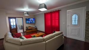 a living room with a couch and red curtains at Levada Nova House in Ribeira Brava