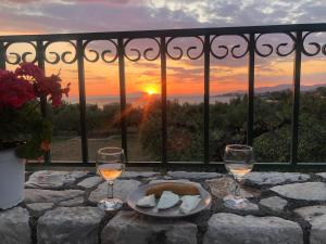 a table with two glasses of wine and a plate of cheese at Villa Pefnos in Agios Nikolaos