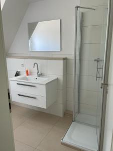 uma casa de banho branca com um lavatório e um chuveiro em Diner Nord 2 em Ostercappeln