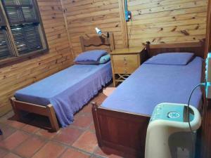 two beds in a room with wooden walls at Terrinha Nosso Paraíso in São Carlos