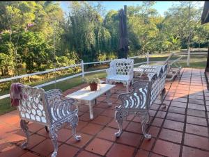 três cadeiras brancas e uma mesa num pátio em Terrinha Nosso Paraíso em São Carlos