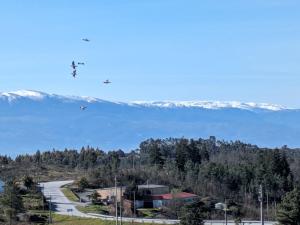 a helicopter flies over a road with snow covered mountains at Casas da Fraga - Serra da Estrela in Fornos de Algodres