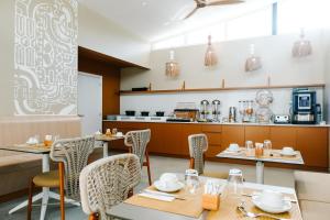 un restaurante con mesas y sillas y una cocina en Niu Beach Hôtel Moorea en Moorea