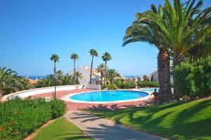 einen großen Pool mit Palmen und dem Meer in der Unterkunft Apartment in Santa Pola with parking space in Santa Pola