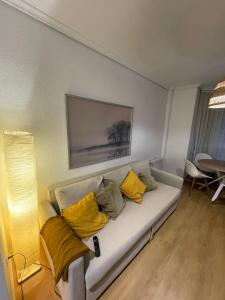 una sala de estar con un sofá blanco con almohadas amarillas en Precioso alojamiento céntrico con garaje, terraza y aire acondicionado en Albacete
