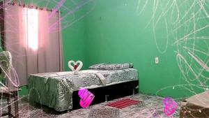 Cette chambre verte comprend un petit lit et une table. dans l'établissement Pousda kurasi alter, à Alter do Chão