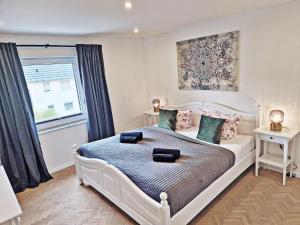 1 dormitorio con cama blanca y ventana en FeelGood 212 qm Ferienhaus mit 2 Apartments - Garten, Grill & Sauna!, en Schauenburg