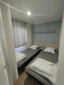 2 Betten in einem kleinen Zimmer mit Spiegel in der Unterkunft Terre de Provence, mobil home camping 4* in Nans-les-Pins