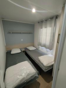 ein kleines Zimmer mit 2 Betten und einem Fenster in der Unterkunft Terre de Provence, mobil home camping 4* in Nans-les-Pins
