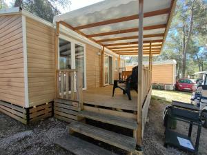 eine Holzhütte mit einer Veranda und einem Stuhl auf einer Terrasse in der Unterkunft Terre de Provence, mobil home camping 4* in Nans-les-Pins