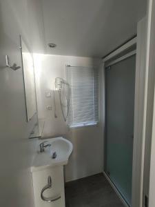ein weißes Bad mit einem Waschbecken und einer Dusche in der Unterkunft Terre de Provence, mobil home camping 4* in Nans-les-Pins