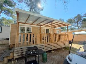 eine Holzhütte mit einer Terrasse und einem Grill in der Unterkunft Terre de Provence, mobil home camping 4* in Nans-les-Pins