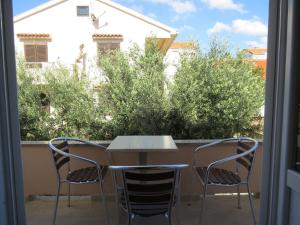 a table and chairs on a balcony with trees at Apartment and Rooms Amenka in Novalja