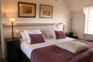 - une chambre dotée d'un grand lit avec des oreillers violets et blancs dans l'établissement Auberge de Campveerse Toren, à Veere