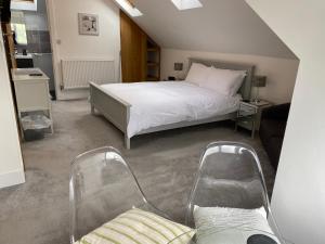 a bedroom with a bed and two chairs at Linton Luxury Holiday Home in Mevagissey