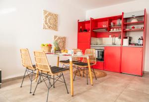 a kitchen with red cabinets and a table and chairs at sunlight ornos suites, private hot tub in Mikonos