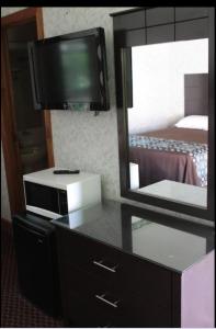 a room with a tv and a dresser with a mirror at Wagon Wheel Inn in Lenox