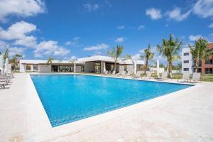 a swimming pool with chairs and a building at Costal condo with gym and Olympic pool in Punta Cana