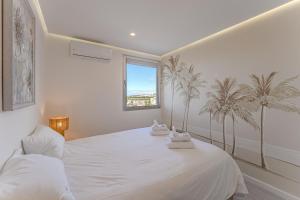 una camera da letto bianca con palme sul muro di Ocean Garden Sunset & Sunrise - heated pool ad Adeje