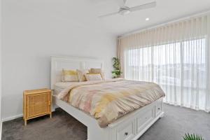 a white bedroom with a large bed and a window at Valley Way in Lennox Head