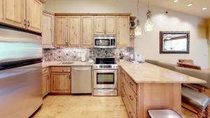 uma cozinha com armários de madeira e electrodomésticos de aço inoxidável em Terracehouse - CoralTree Residence Collection em Snowmass Village
