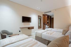 a hotel room with three beds and a tv at فندق روحة المقام in Ajyad