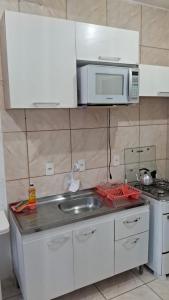 a small kitchen with a sink and a microwave at Apartamento próximo ao Aeroporto de Florianópolis. in Florianópolis