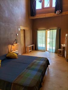 a bedroom with a bed in a room with windows at Mas la Llum, la casa de palla in Arens de Lledó