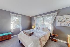 een slaapkamer met een bed met witte lakens en 2 ramen bij Sunset House in Spring Hill