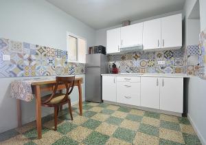 - une cuisine avec des placards blancs, une table et un réfrigérateur dans l'établissement A Casa Vella de Laura, à Vilagarcía de Arousa