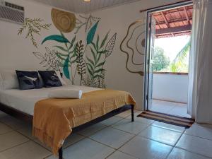 a bedroom with a bed with a mural on the wall at Espaço Circular in Itacaré