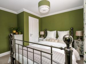 a bedroom with green walls and a bed at Coral House in Cromer
