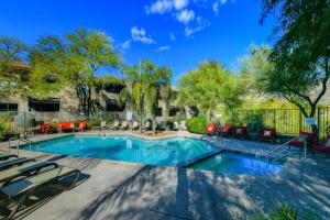 a swimming pool with lounge chairs and tables in a yard at The Greens at Ventana Canyon #1205 in Tucson