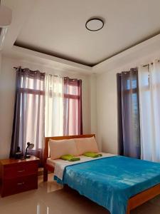 a bedroom with a bed with blue sheets and windows at Michael's Apartment in Moalboal